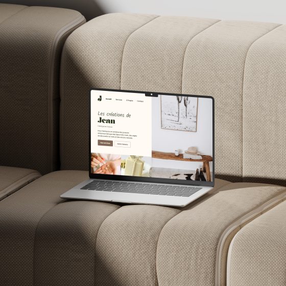 Macbook posé sur un canapé avec le site des créations de Jean sur l'écran